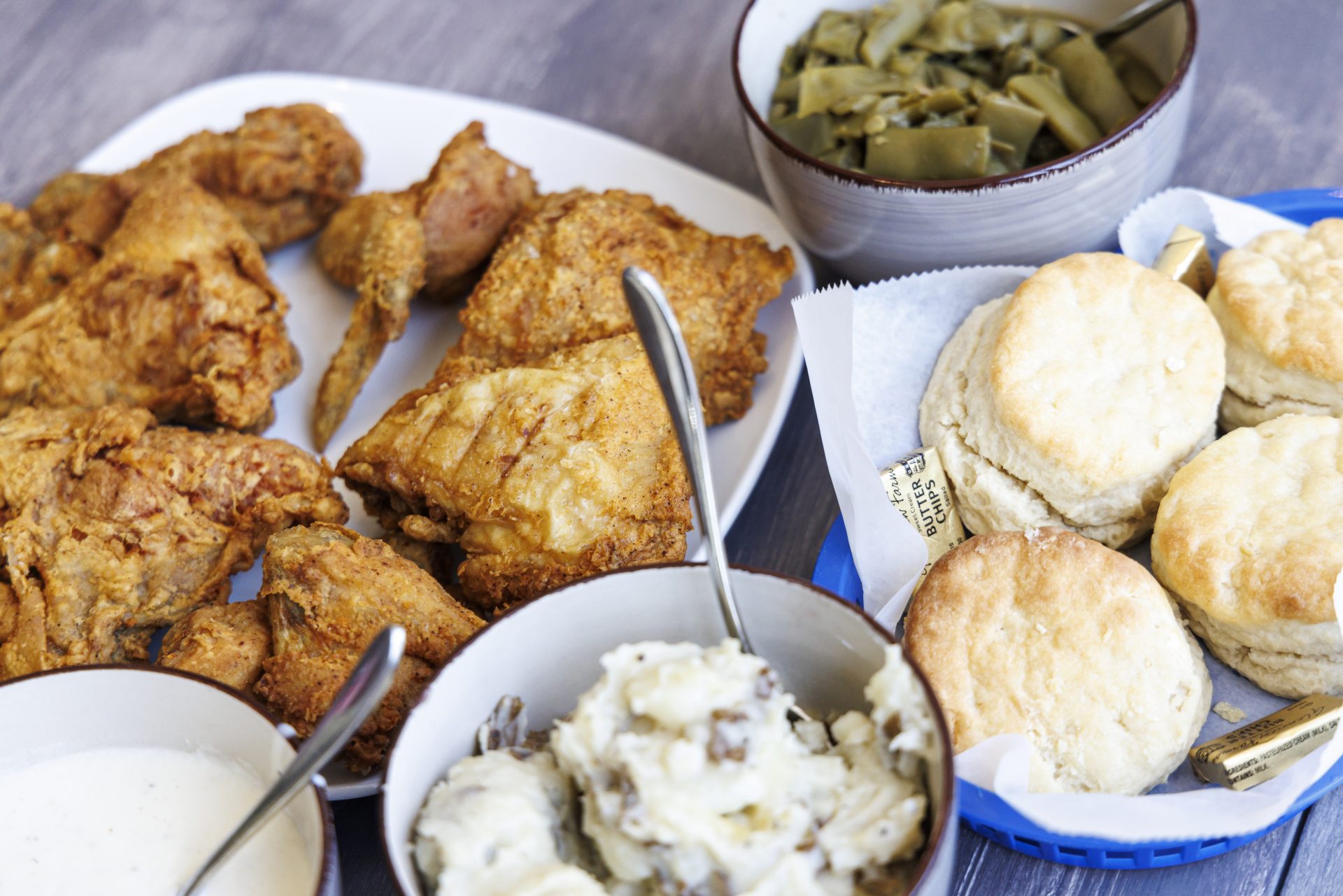 dishes of food on table: fried chicken, green beans, smashed potatoes, biscuits