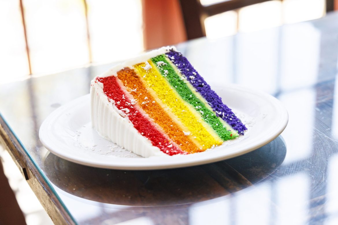 plate of rainbow layer cake with white frosting