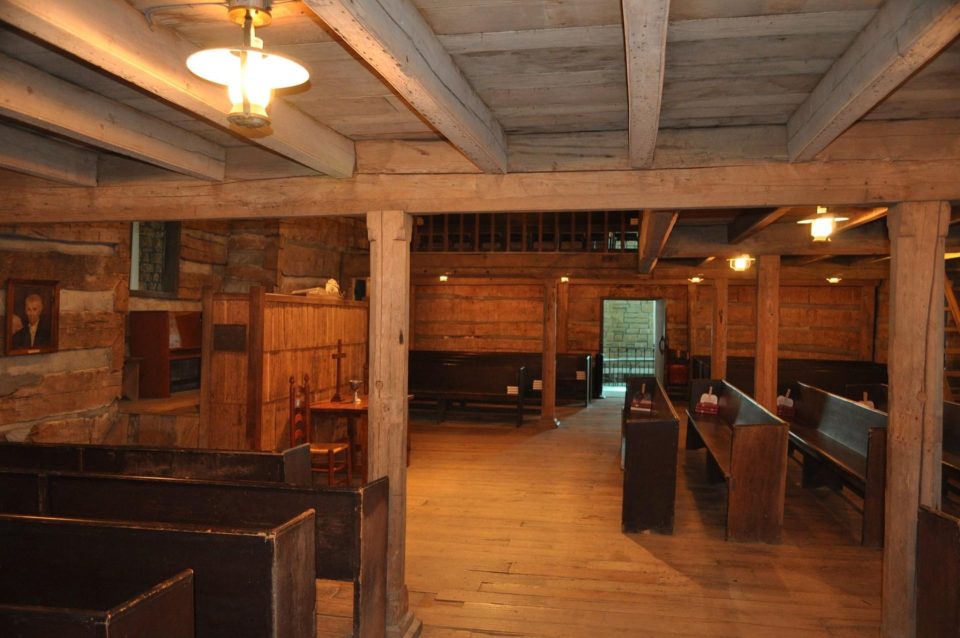 rows of church pews in log cabin building